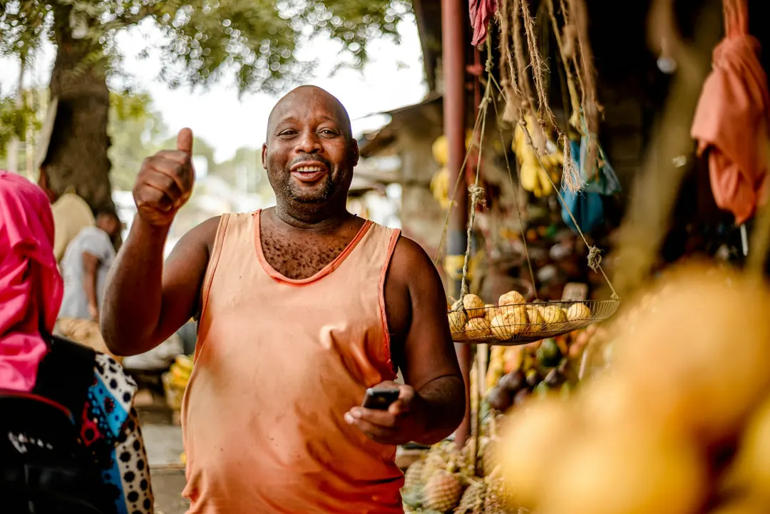 Un vendeur souriant devant son étal de fruits
