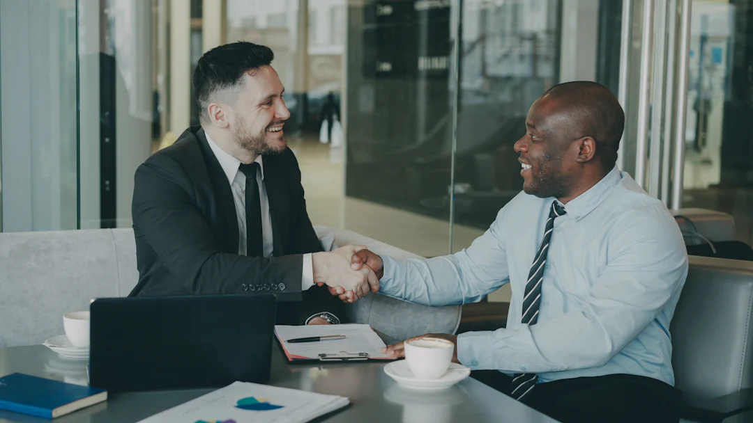 Deux professionnels se serrent la main autour d'une table de travail