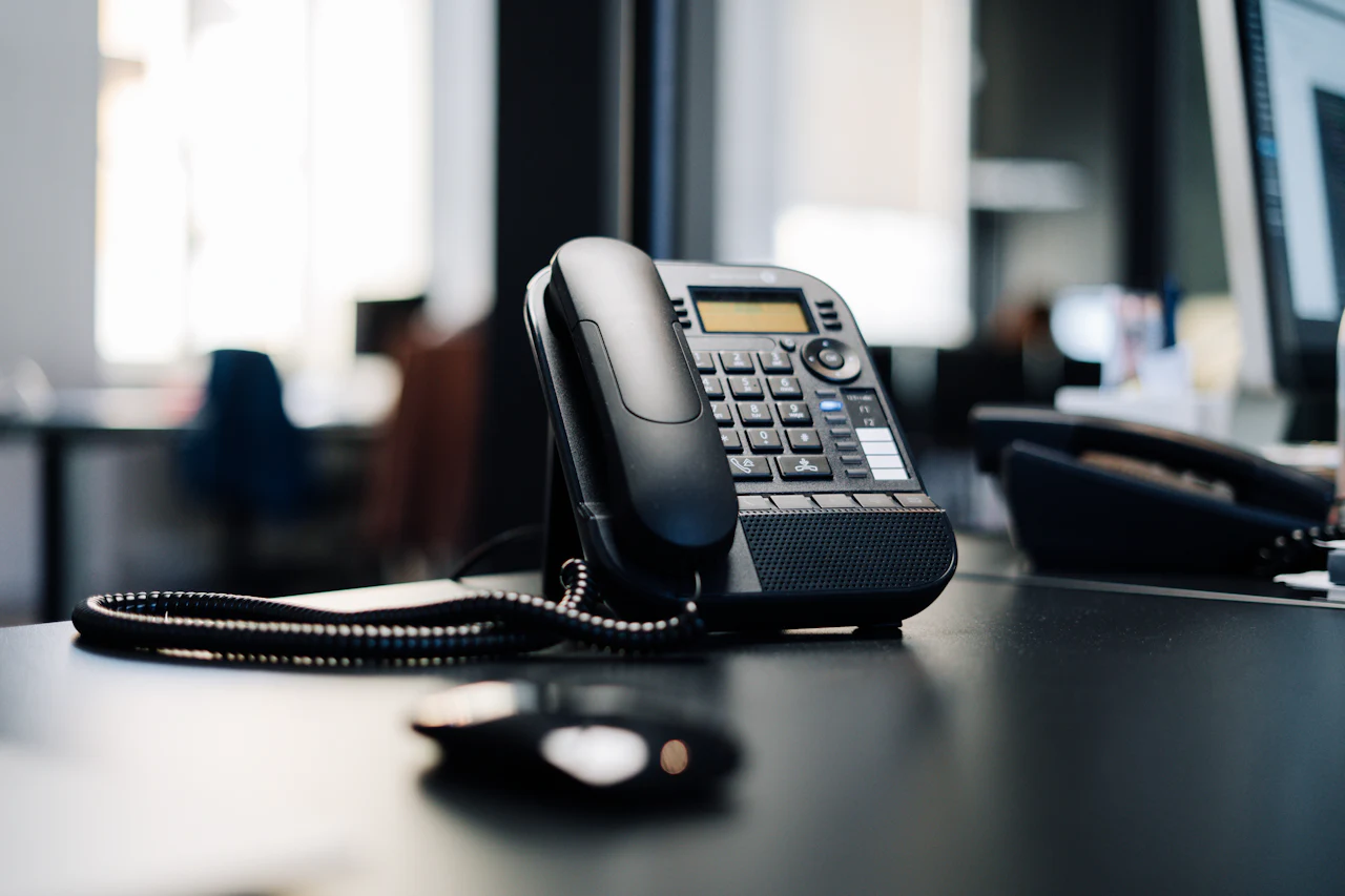 Un téléphone de bureau posé sur une table sombre